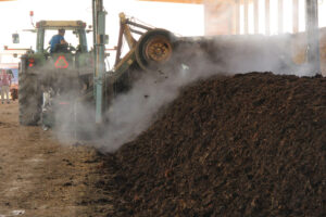 A tractor turns manure to assist with composting.